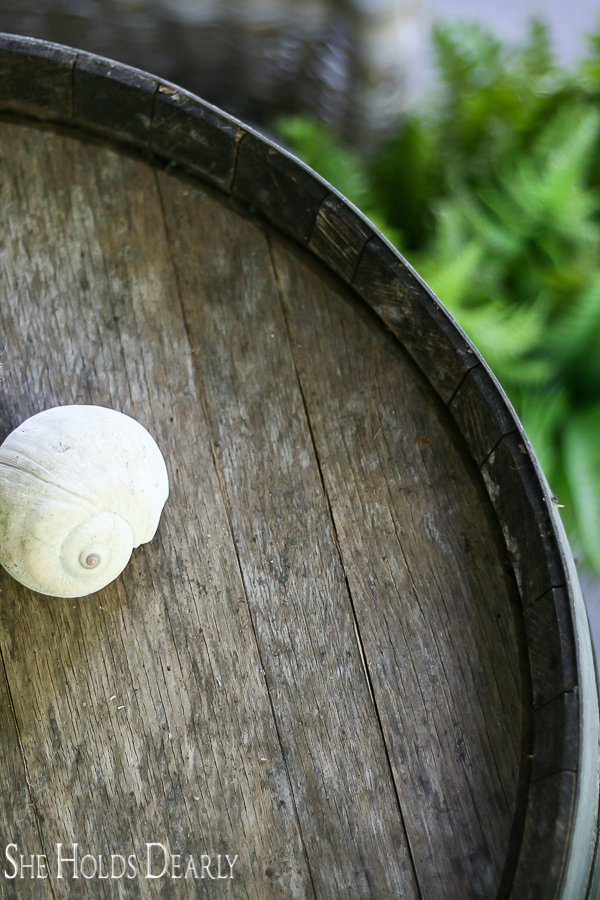 Seashells and ferns on a whiskey barrel for natural, summer porch decor
