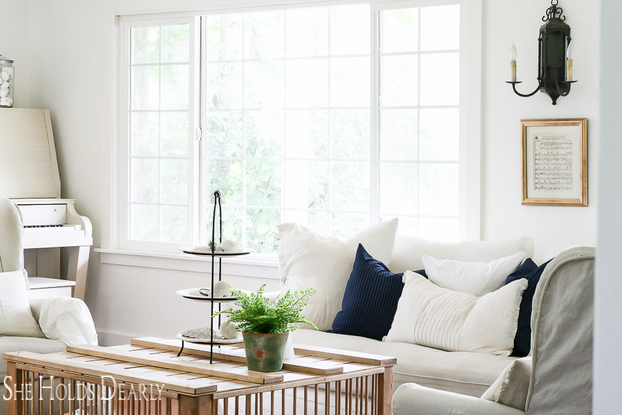 Farmhouse Summer Decorating white slipcovered couch, navy pinstripe pillows, chicken crate coffee table