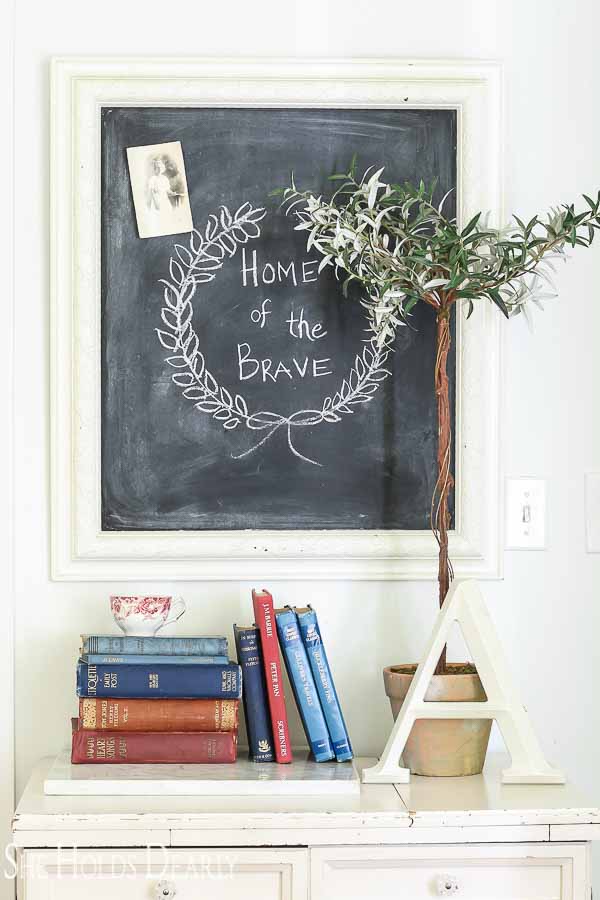 Home of the Brave chalkboard, olive topiary and antique books